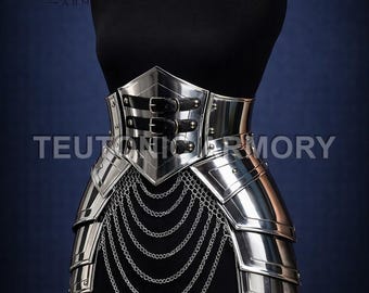 May include: A silver-colored metal armor piece, displayed on a black mannequin. The armor features a waist belt with two black leather straps and a series of hanging chainmail. The text "TEUTONIC ARMORY" is visible.