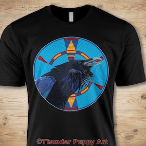 May include: Black t-shirt with a graphic of a raven in a blue, red, and yellow circle. The text "Thunder Puppy Art" is at the bottom of the shirt.