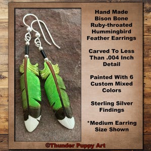 May include: Handmade bison bone earrings featuring ruby-throated hummingbird feather designs. The earrings are painted with six custom mixed colors and have sterling silver findings. The feather earrings are carved to less than .004 inch detail.