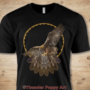 May include: Black t-shirt with a golden eagle design. The eagle is flying with its wings spread wide and is surrounded by a golden circle. The eagle's feathers are detailed and realistic. The text "Thunder Puppy Art" is at the bottom of the shirt.