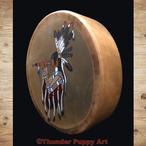 May include: A hand-painted Native American drum featuring a depiction of a person playing a flute. The drum is brown with a light brown background and has a colourful design with red, blue, yellow, and white accents. The text "&copy;Thunder Puppy Art" is at the bottom of the drum.