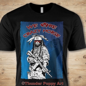 May include: Black t-shirt with a graphic of a Native American man holding a rifle. The graphic is in black and white with red accents. The text "WE ARE CRAZY HORSE" is written in red on the graphic. The text "©Thunder Puppy Art" is written in white at the bottom of the graphic.