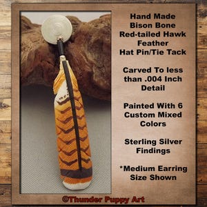 May include: A handmade hat pin or tie tack with a red-tailed hawk feather design. The feather is painted with six custom mixed colours and carved in detail. The pin has sterling silver findings.