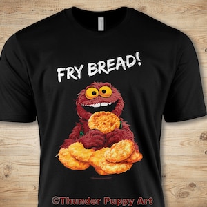 May include: Black t-shirt featuring a red furry monster holding a pile of fried bread. The text "Fry Bread!" is printed in white above the monster.