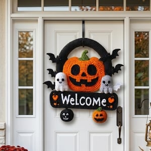 Puede incluir: Una corona de Halloween hecha a mano con una gran calabaza naranja, murciélagos negros y dos pequeños fantasmas. La corona tiene la palabra "Welcome" en un letrero negro. Cuelga de una puerta blanca.