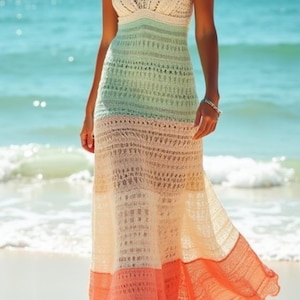 Op de afbeelding: Een veelkleurige gehaakte maxi-jurk met een V-hals en spaghettibandjes. De jurk loopt over van wit naar mintgroen, dan naar perzik en koraal. De jurk wordt gedragen op een strand met de oceaan op de achtergrond.