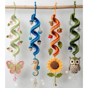Pode incluir: Quatro ornamentos em espiral de crochê coloridos pendurados em uma vara de madeira. Cada ornamento apresenta um design único: uma borboleta, um cavalo-marinho, um girassol e uma coruja. Os ornamentos são adornados com detalhes de crochê e contas penduradas.