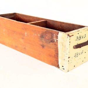 May include: A wooden box with two compartments, painted white on the front with the text "3/8 x 3" and "3/8 x 4".