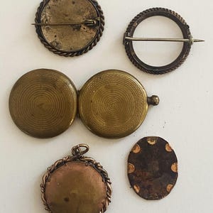May include: Five antique brass locket pendants with different designs. Some have a rope-like border, others have a circular pattern. One locket is open, revealing a circular pattern inside.