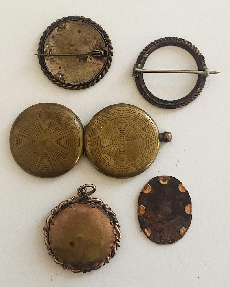 May include: Five antique brass locket pendants with different designs. Some have a rope-like border, others have a circular pattern. One locket is open, revealing a circular pattern inside.