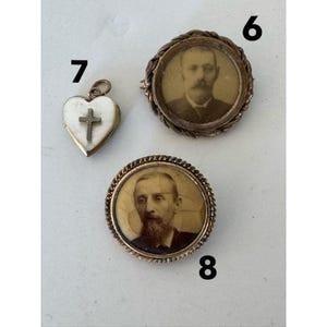 May include: Three antique gold-toned brooches with portraits. One brooch features a heart-shaped locket with a cross inside. Another brooch features a round portrait of a man with a mustache and beard. The third brooch features a round portrait of a man with a beard.