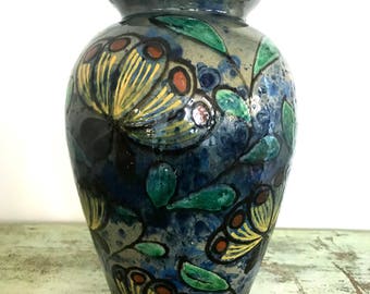 May include: A blue ceramic vase with a floral design. The vase is decorated with yellow, green, and red flowers.