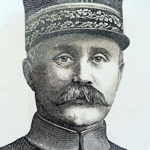 May include: A black and white engraving of a man in a military uniform. He is wearing a hat with a band and a mustache. The engraving is on a white background.