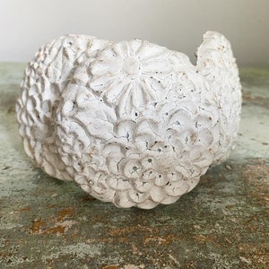 May include: White ceramic planter with a floral design. The planter is made of a textured material and has a distressed look.