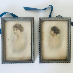 May include: Two antique silver-toned picture frames with black and white photographs of women. The frames have a decorative border.