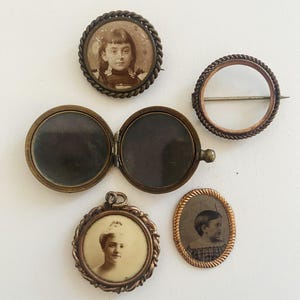 May include: Five antique locket style brooches with ornate gold frames. Each locket features a black and white photograph of a person. Two of the lockets are round, two are oval, and one is a simple circle.