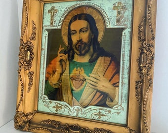 May include: Ornate gold-framed religious artwork featuring a portrait of Jesus Christ. The image depicts Jesus with a halo, a sacred heart, and a serene expression. The frame has detailed carvings and a distressed finish, adding to its vintage aesthetic.