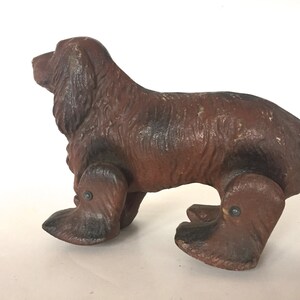 May include: A brown and black toy dog with wheels for legs. The dog is made of wood and has a realistic appearance.