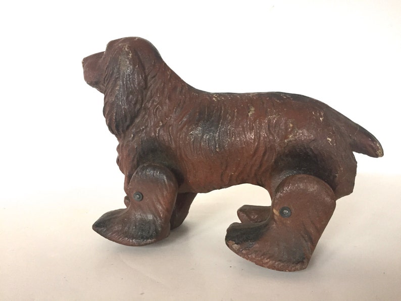 May include: A brown and black toy dog with wheels for legs. The dog is made of wood and has a realistic appearance.