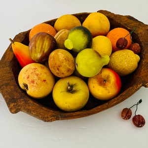 May include: A wooden bowl filled with a variety of colorful fruit, including apples, pears, lemons, and figs. The fruit is arranged in a decorative pattern and appears to be made of wax or plastic.