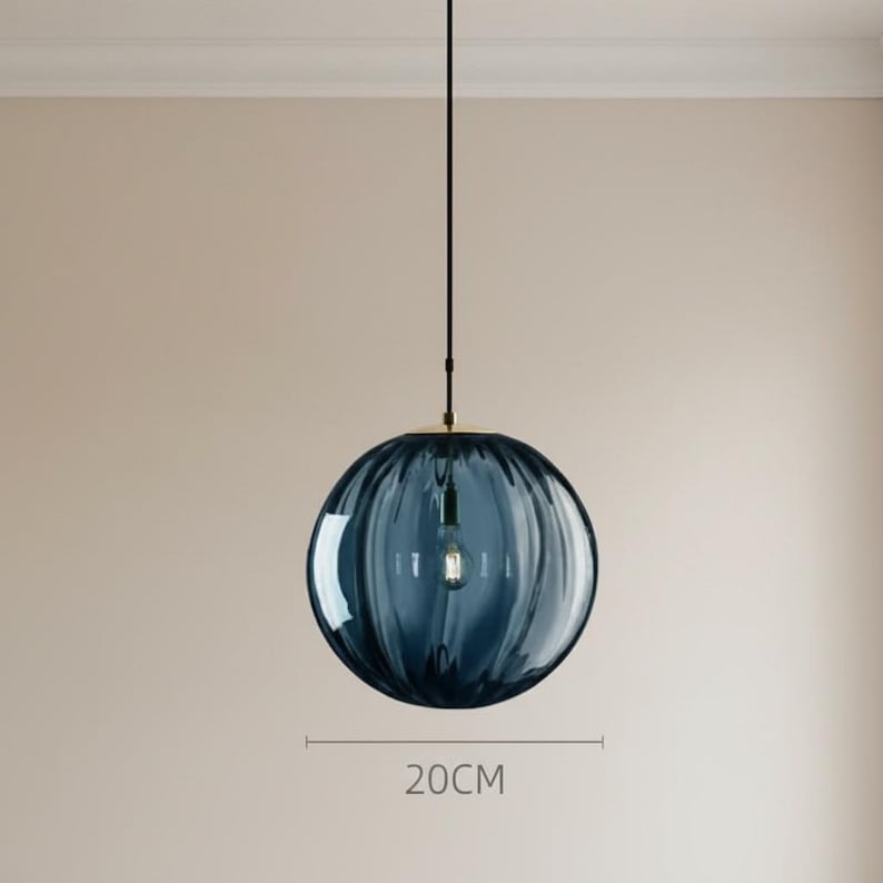 May include: A blue glass pendant light with a ribbed texture, hanging from a black cord. The light bulb is visible inside the spherical shade. The diameter of the shade is 20cm.