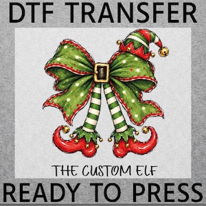 May include: A DTF TRANSFER graphic featuring a large green bow with red trim and a central buckle, attached to two striped green and white elf legs wearing curled red shoes with gold bells. The text reads DTF TRANSFER, THE CUSTOM ELF, READY TO PRESS.