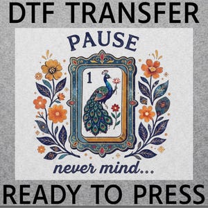 May include: A DTF transfer sheet featuring the text PAUSE at the top and never mind... at the bottom. The center shows a rectangular frame containing a peacock and the number 1, flanked by orange and blue floral illustrations. READY TO PRESS.