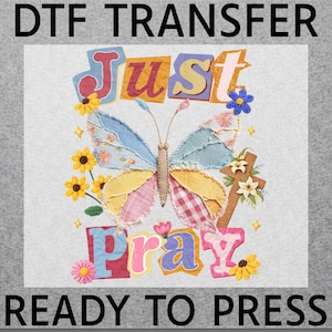 May include: A DTF transfer design featuring a colorful butterfly with patchwork wings and the words "Just Pray." The design includes flowers, a cross, and the text "READY TO PRESS."