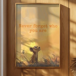 Puede incluir: Una lámina de arte enmarcada que muestra a un cachorro de león con una corona amarilla brillante, sobre un paisaje de tonos dorados cálidos. El texto "Never forget who you are" aparece impreso en una fuente naranja suave en la parte superior.