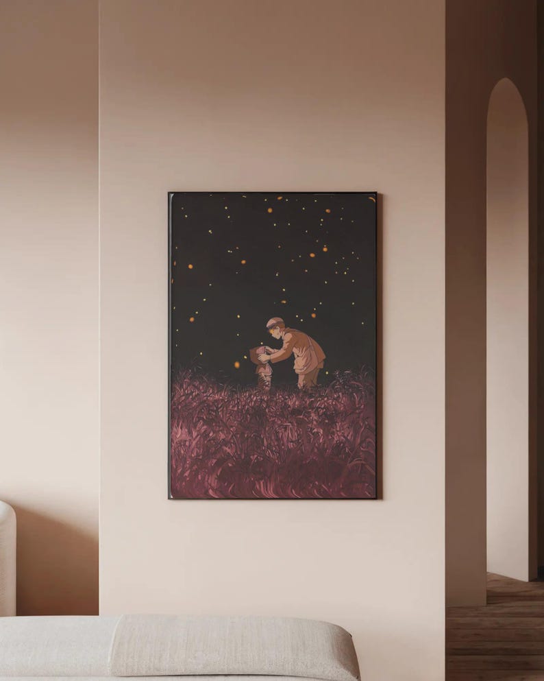 May include: A framed art print depicts a person in a brown coat interacting with another figure in a field of tall, reddish-purple grass under a dark sky with glowing orbs. The artwork is displayed on a light-colored wall.