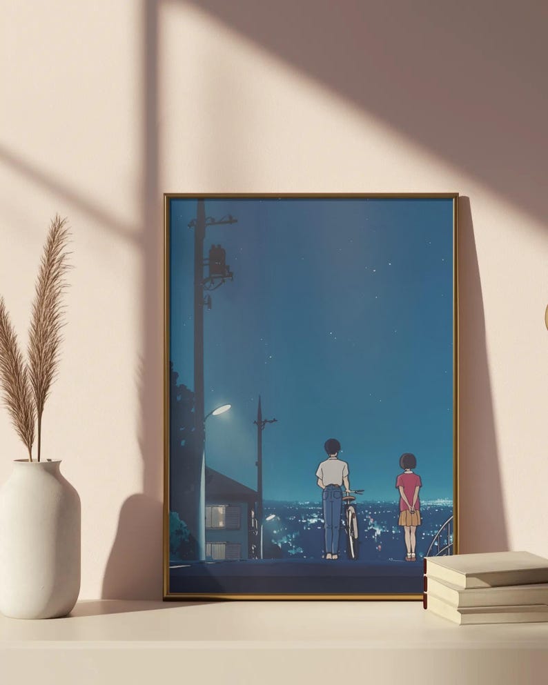 Może przedstawiać: Oprawiony wydruk artystyczny z ilustracją w stylu anime przedstawiającą dwie postacie na wzg&oacute;rzu z widokiem na miasto nocą. Grafika ma złotą ramę i przedstawia chłopca z rowerem i dziewczynkę. Niebo jest ciemnoniebieskie z gwiazdami.