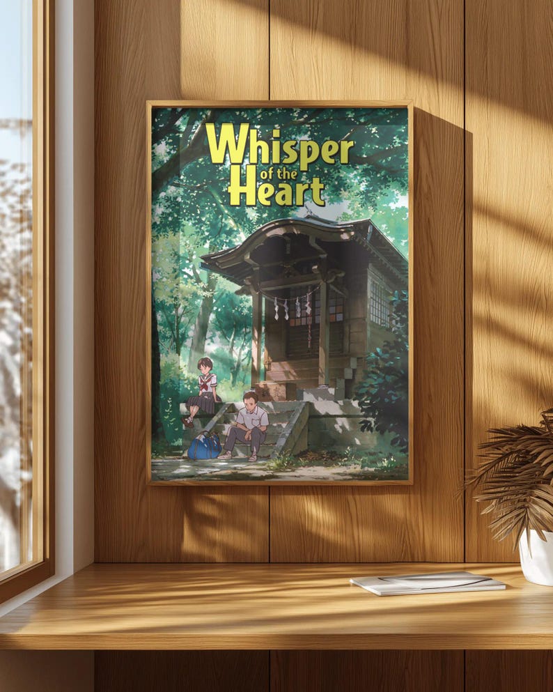 May include: A framed poster with the title "Whisper of the Heart" in yellow. The anime artwork shows a wooden building, trees, and three characters. The poster is mounted on a wooden wall, with a wooden desk in the foreground.