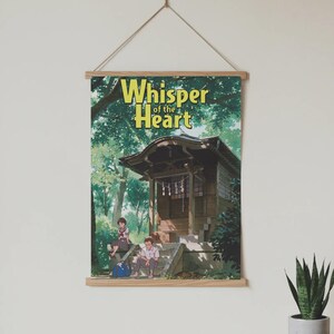 May include: A poster with the text "Whisper of the Heart" in yellow lettering, hanging from a wooden frame. The poster depicts an anime scene of a Japanese shrine with two people sitting on the steps.