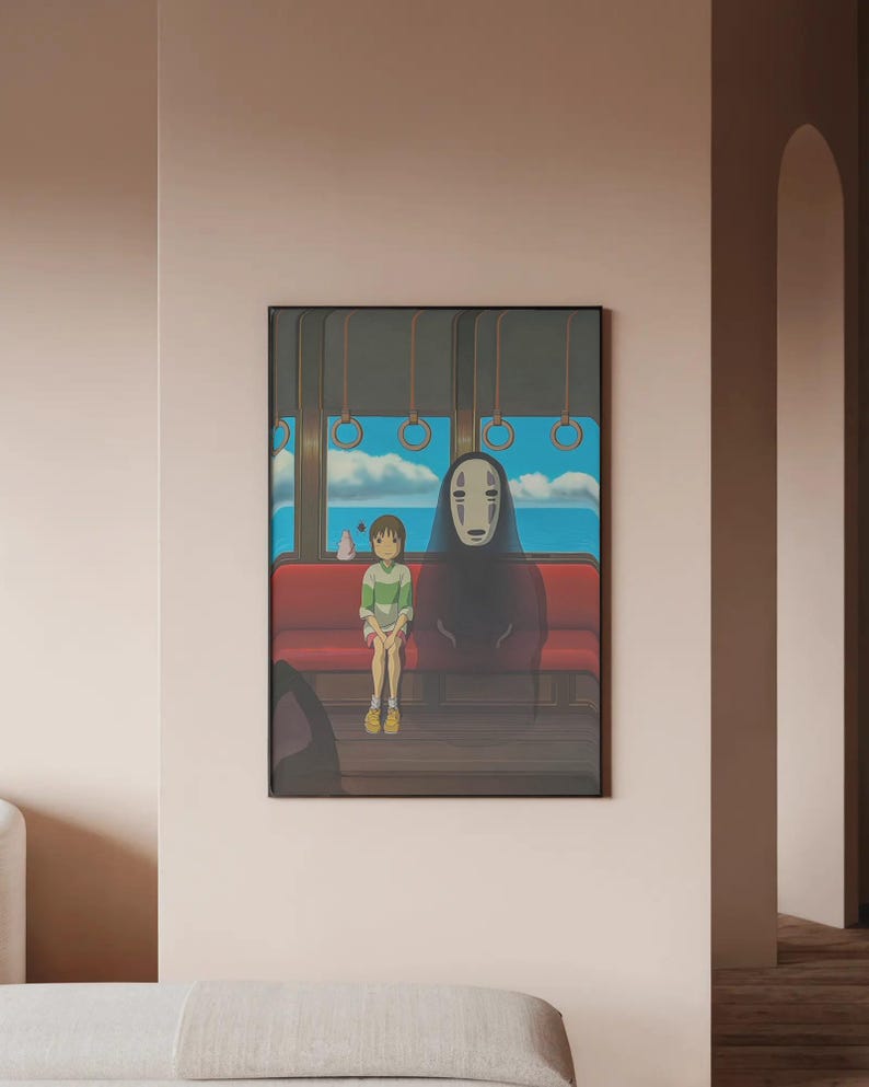 May include: Framed art print featuring a scene from an animated film. The artwork depicts two figures seated on a red bench inside a train car, with a blue sky and ocean visible through the windows. The figures include a young person and a tall, dark figure.