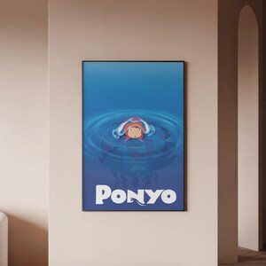 Pu&ograve; includere: Poster incorniciato con la parola "Ponyo" in testo bianco, raffigurante un personaggio animato nell'acqua. Il personaggio ha i capelli rossi ed &egrave; circondato da acqua blu. Il poster &egrave; in una cornice nera ed &egrave; appeso a un muro beige.