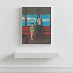 May include: Framed art print featuring a scene from an animated film. A young person in a green and white striped shirt sits on a red bench next to a tall, dark figure with a white mask. The background shows a blue sky and ocean.