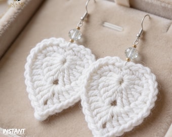 May include: A pair of white, crocheted leaf-shaped earrings. Each earring features a silver-colored hook, a clear bead, and a gold-colored bead. The earrings are displayed in a beige jewelry box. The text "INSTANT DOWNLOAD PDF" is visible.