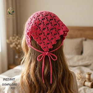 May include: A handmade, bright pink crochet headscarf with a floral pattern. The headscarf is tied at the back with a bow. The words "INSTANT DOWNLOAD PDF" are visible in the lower left corner.
