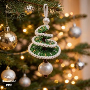 May include: A spiral-shaped Christmas tree ornament crocheted in dark green yarn with white trim and metallic gold accents. The ornament features a white pearl bead at the top loop and a larger white pearl bead hanging from the bottom center point.