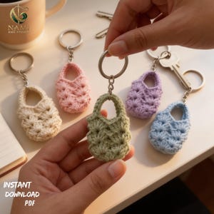 May include: A collection of handmade crochet bag keychains in various pastel colors: cream, pink, green, purple, and blue. Each keychain features a small, detailed bag design with a silver keyring. The image includes the text "INSTANT DOWNLOAD PDF".