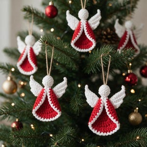 May include: Four handmade crochet angel ornaments hanging on a green pine tree. Each angel features a round white head, white wings, and a red dress with a white crocheted border. A thin tan string is attached to the top of each angel for hanging.