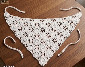 May include: A white triangular crochet bandana featuring a repeating floral motif pattern. The accessory includes long crocheted ties at the top corners and a small rectangular brown tag attached to one of the lower side edges with the letter M.