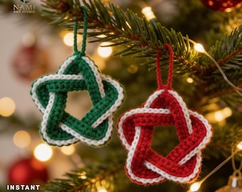 May include: Two five-pointed star ornaments crafted from yarn, one in green and white and the other in red and white. Each star features a woven, knotted design with a matching yarn loop at the top for hanging. The text NAMI EMB STUDIO is visible.