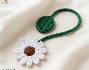 May include: A crochet bookmark featuring a white daisy flower with a brown center, attached to a long green stem that ends in a single green leaf. The text NAMI EMB STUDIO and INSTANT DOWNLOAD PDF are visible in the corners of the image.