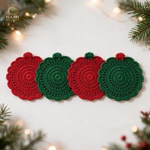 May include: Four round crochet coasters arranged in a row, alternating between red and dark green colors. Each coaster features a scalloped edge and a small loop at the top, resembling a Christmas ornament. The yarn texture is visible.