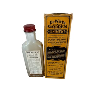 May include: A clear glass bottle with a red screw cap and a white label reading DeWitt's Golden Liniment, accompanied by a tall yellow cardboard box featuring black text detailing ingredients, usage instructions, and a 35 ml volume.
