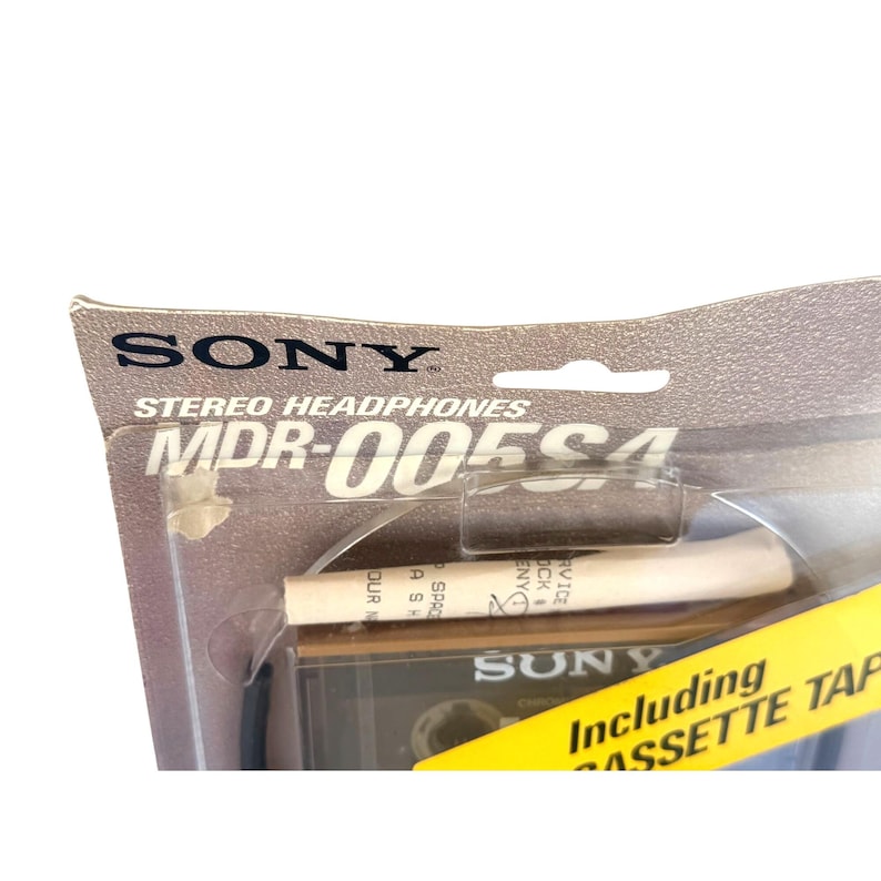May include: A Sony MDR-005S4 stereo headphones package with a clear plastic blister pack. The cardboard backing features the Sony logo and model number. A yellow promotional strip across the bottom reads Including CASSETTE TAPE.