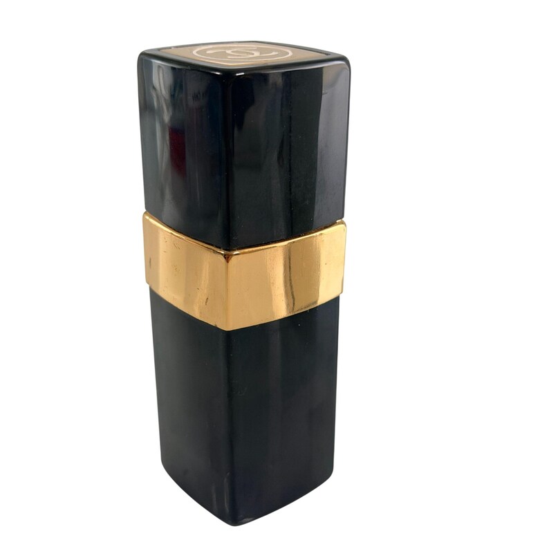 May include: A black rectangular perfume bottle with a gold band around the middle. The top of the bottle is black with a gold logo. The bottle has a sleek, modern design.