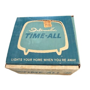 Può includere: Una scatola blu vintage con le parole "Intermatic TIME-ALL" in bianco e verde acqua. La scatola ha un design retrò con un'immagine stilizzata di un televisore. È visibile anche il testo "LIGHTS YOUR HOME WHEN YOU'RE AWAY".