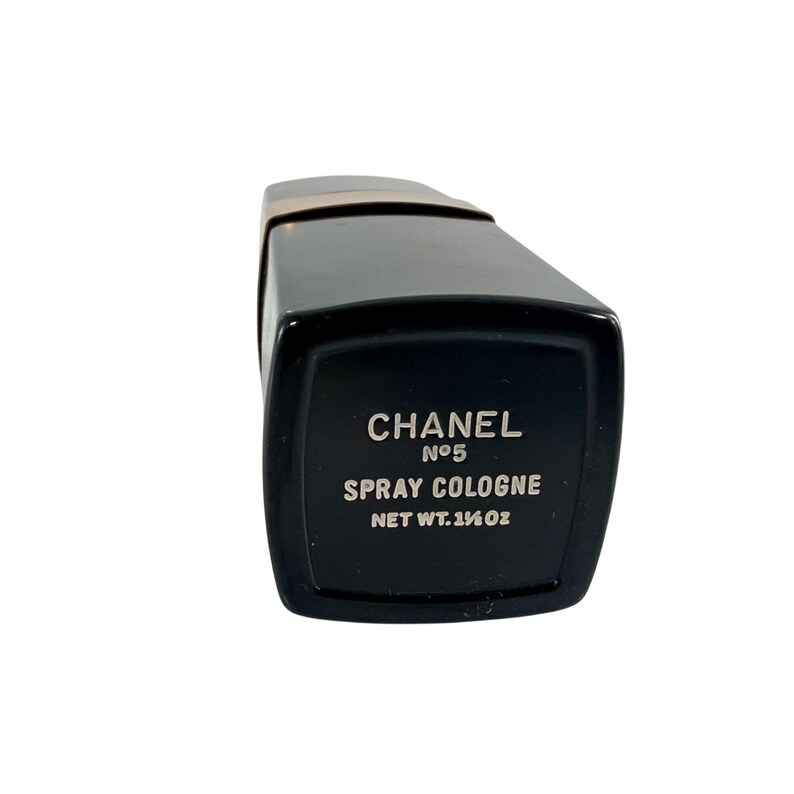 May include: Black Chanel No. 5 spray cologne bottle. The rectangular bottle has a black body with gold accents and a black cap. The label reads "CHANEL No. 5 SPRAY COLOGNE NET WT. 1&frac14; OZ."